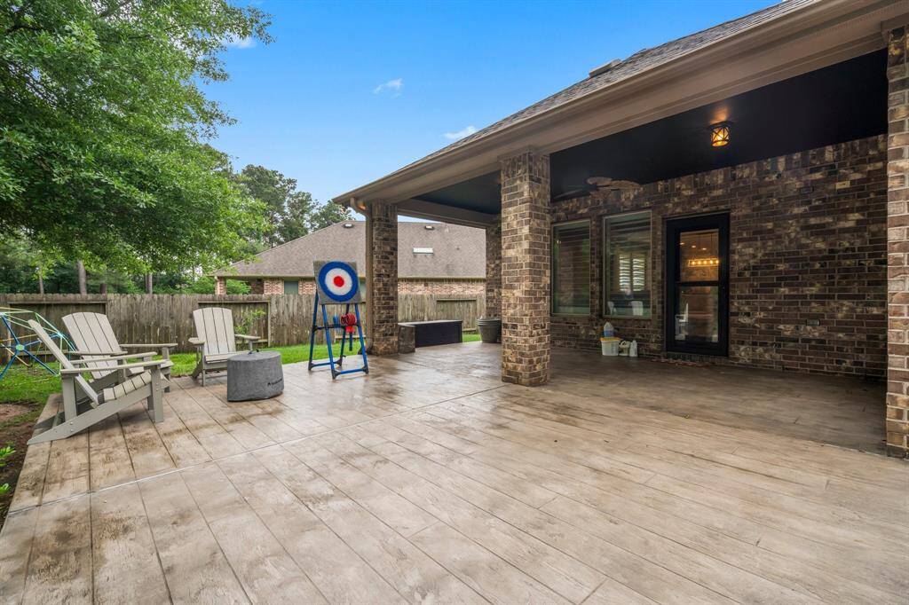 This covered patio, complete with ceiling lighting and a ceiling fan, provides the perfect shaded retreat, offering peaceful views of the wooded greenbelt that surrounds your private lot, enhancing your privacy. An electrical wall outlet is conveniently installed, making it easy to set up your outdoor TV for relaxing evenings.