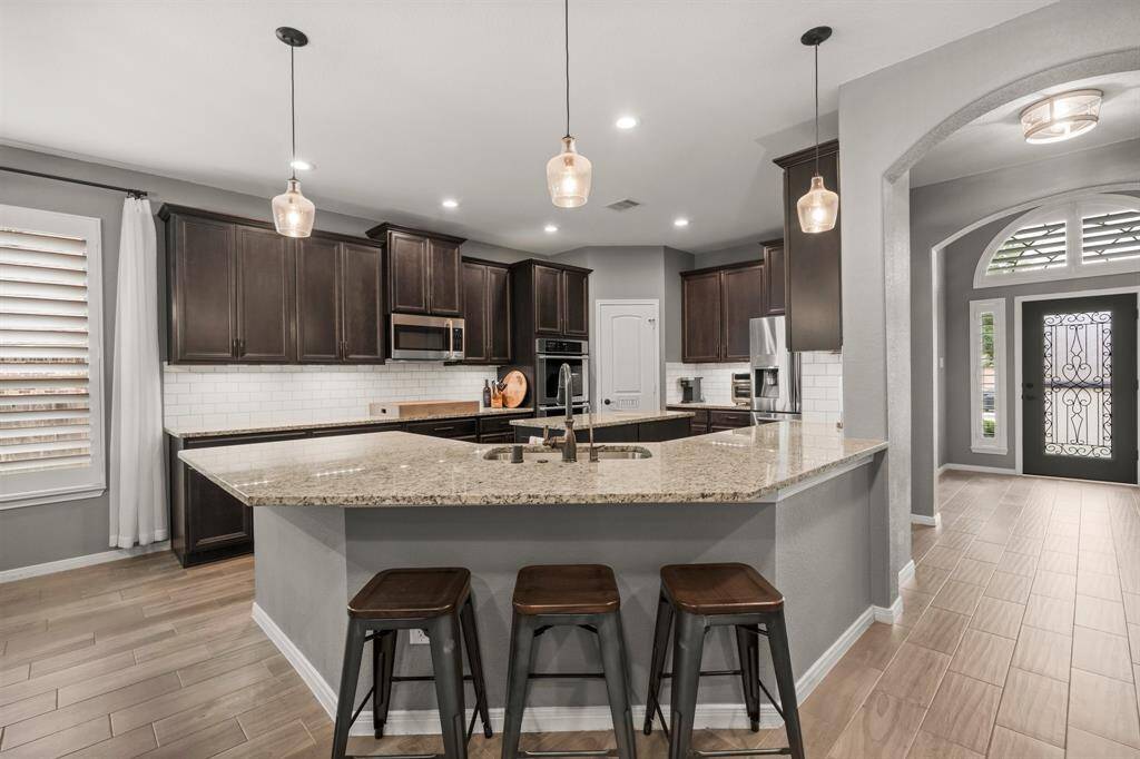 The kitchen is a stunning blend of modern elegance and function, anchored by an impressive peninsula with chic pendant lighting and seating for casual dining, all overlooking the open-concept living space.