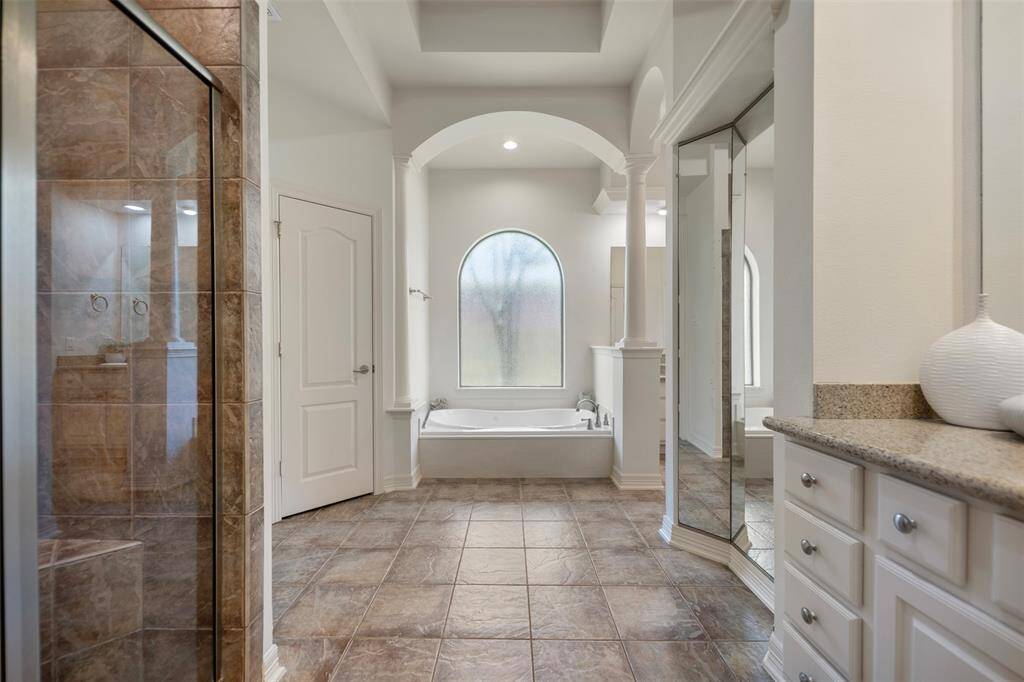 The luxurious primary bath features elegant arched details, a deep soaking tub for ultimate relaxation, and a separate walk-in shower—combining timeless design with spa-like comfort.