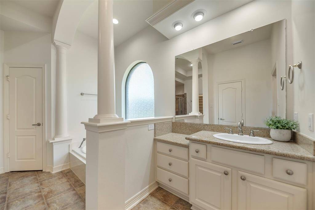 This side of the primary bath features a granite-topped sink with an extended vanity area, perfect for getting ready in comfort and style, with ample space for seating and storage.