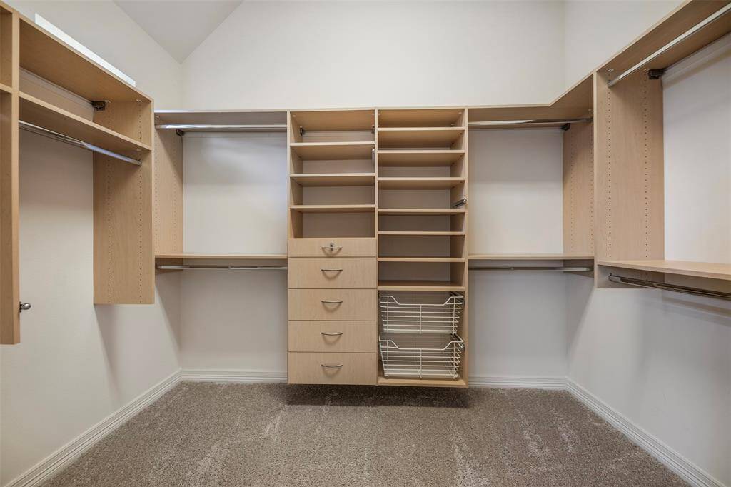 One of two spacious walk-in closets in the primary bath, this well-designed space features built-in drawers, storage racks, and ample hanging space to keep everything organized and easily accessible.