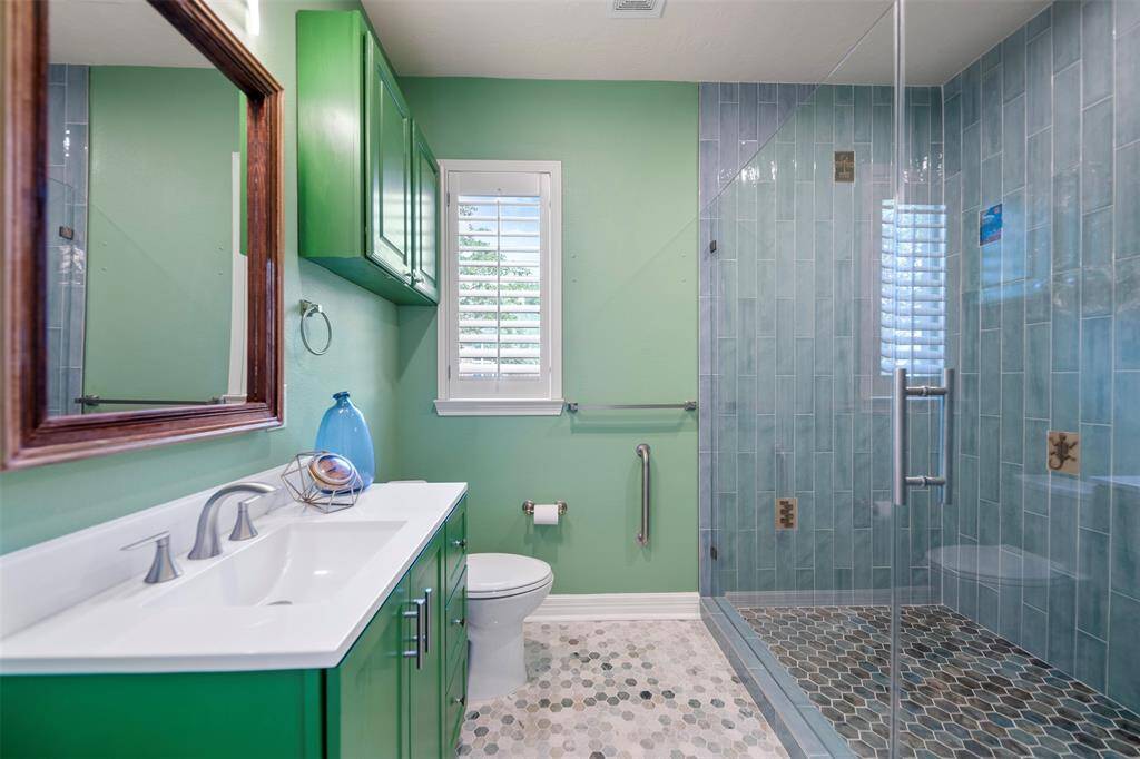 The secondary bath is a true work of art, featuring honeycomb tile floors and vibrant teal shower tiles that create a striking contrast. Custom artwork tiles, hand-crafted by the owner, add a unique and personal touch, making this bathroom a standout feature of the home.