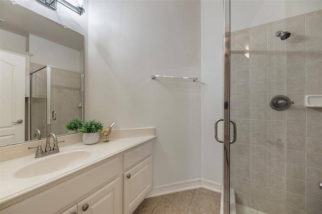The en suite bath of the third bedroom is a spa-like haven, featuring a sleek tile shower with elegant glass doors. The modern design creates a clean, sophisticated look, offering a refreshing and private space.