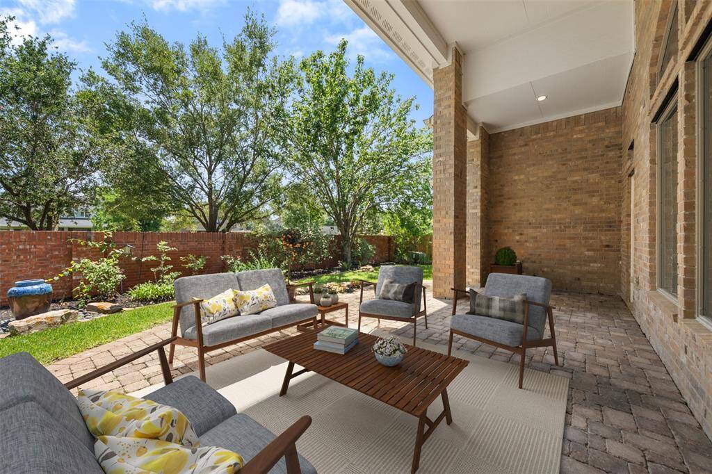 The covered patio provides a serene space for relaxation, framed by lush landscaping. A brick privacy wall surrounds the corner lot, offering both seclusion and a touch of elegance to the outdoor area.(This photo is virtually staged)
