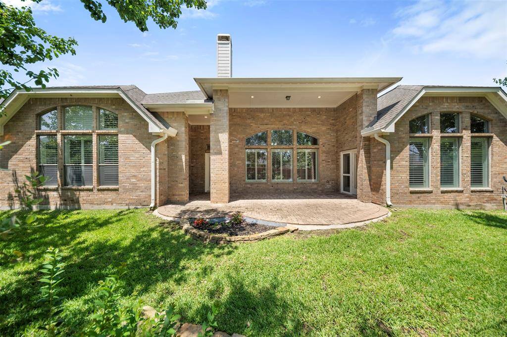 The view from the back of the home showcases an expansive yard, beautifully complemented by well-maintained landscaping and mature trees that provide both shade and natural beauty. The serene outdoor space offers plenty of room for relaxation and entertainment.