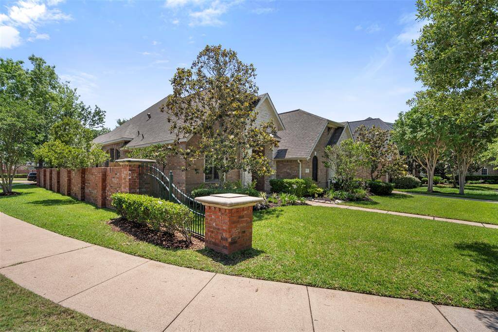 The side of the home features a sturdy brick privacy wall, enhanced with elegant wrought iron fence detailing. This combination offers both security and a refined, timeless look, adding character to the property’s exterior.
