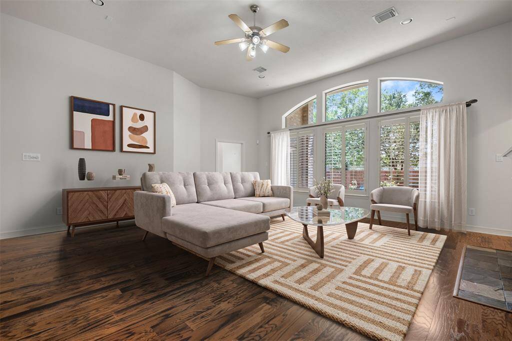The spacious living room featuring rich hardwood floors, a stylish ceiling fan, and large arched windows that flood the space with natural light.(This photo is virtually staged)