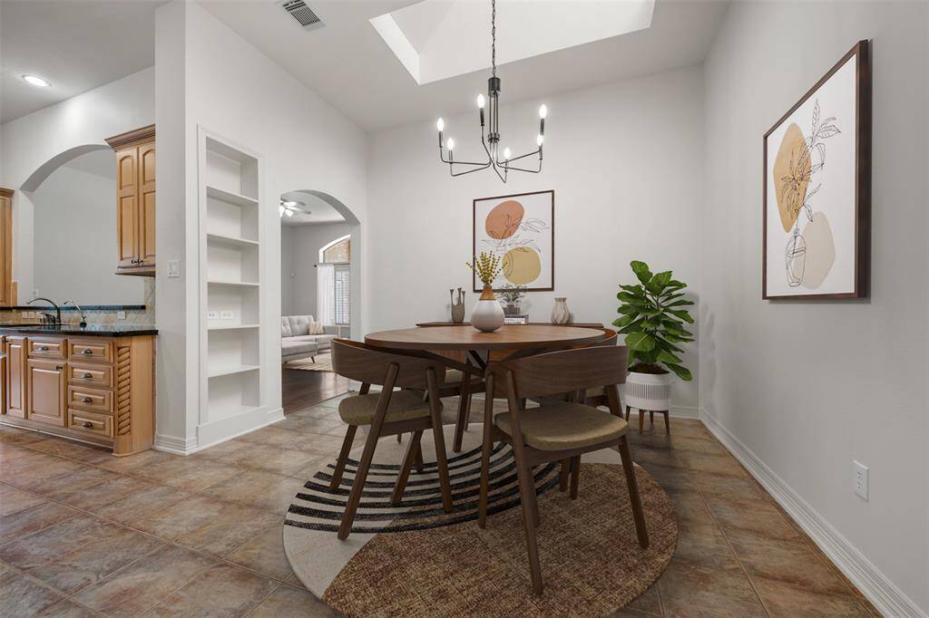 The bright eat-in kitchen features a charming chandelier, skylights that pour in natural light, and a welcoming space perfect for casual dining.(This photo is virtually staged)