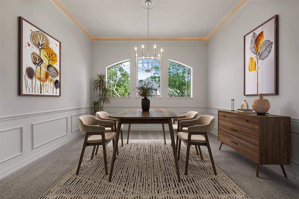 The elegant formal dining room features a striking chandelier, three arched windows, detailed custom woodwork, and ambient cove lighting that highlights the ceiling’s perimeter for a warm, upscale glow.(This photo is virtually staged)