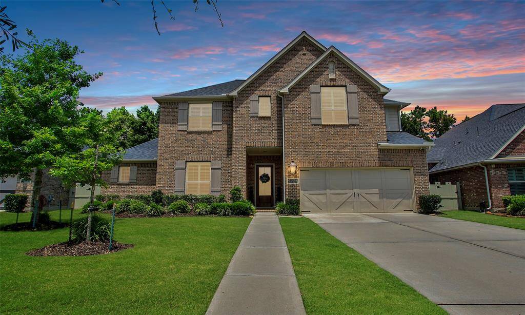 Welcome Home to 9975 Preserve Way. This photo showcases a charming two-story brick home with a neatly manicured lawn, a spacious driveway leading to a two-car garage, and a welcoming front entrance. The house is set against a picturesque sunset sky, enhancing its curb appeal.