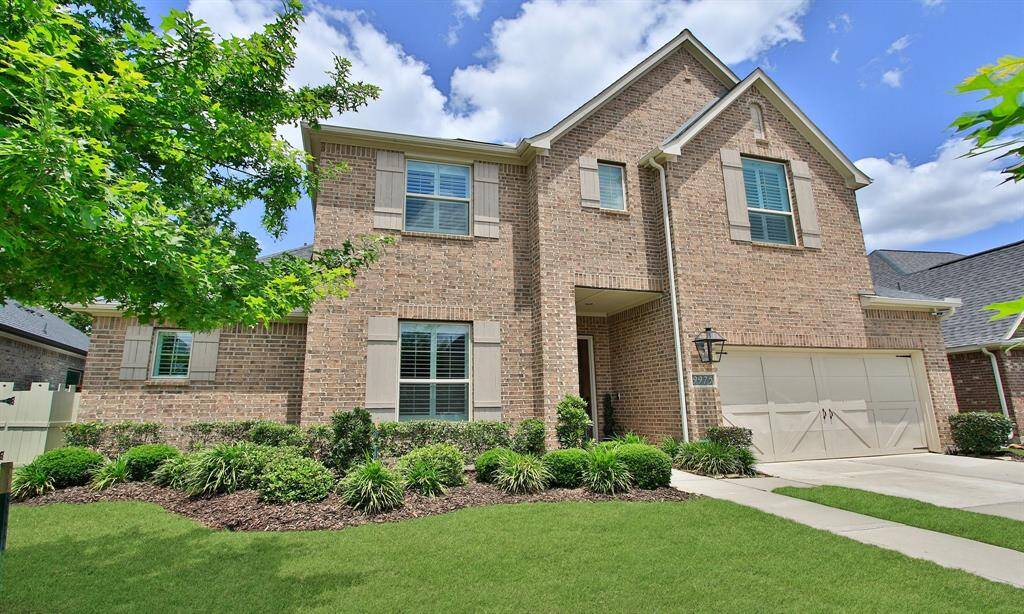 Welcome Home to 9975 Preserve Way. This photo showcases a charming two-story brick home with a neatly manicured lawn, a spacious driveway leading to a two-car garage, and a welcoming front entrance. The house is set against a picturesque sunset sky, enhancing its curb appeal.