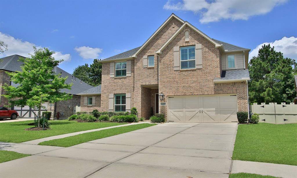 Welcome Home to 9975 Preserve Way. This photo showcases a charming two-story brick home with a neatly manicured lawn, a spacious driveway leading to a two-car garage, and a welcoming front entrance. The house is set against a picturesque sunset sky, enhancing its curb appeal.