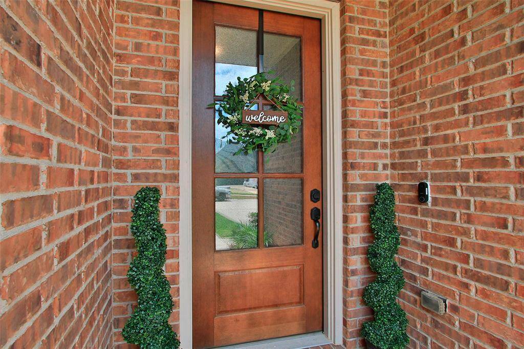 Charming brick entryway with a wooden front door welcomes you home.