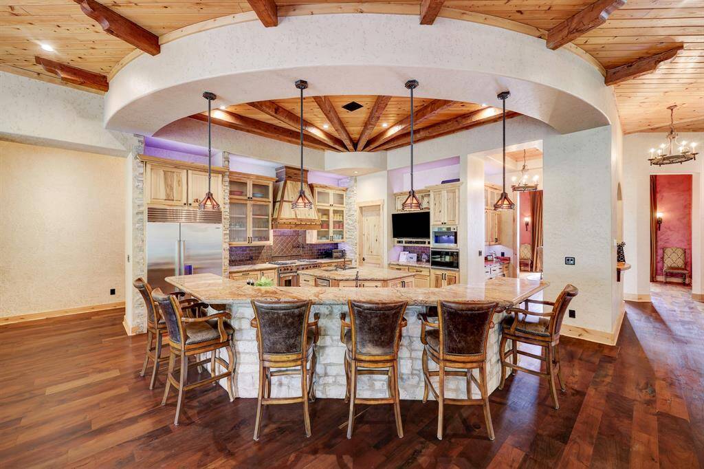 The wagon wheel wood features draw the eye into the rustic stone and wood driven kitchen.