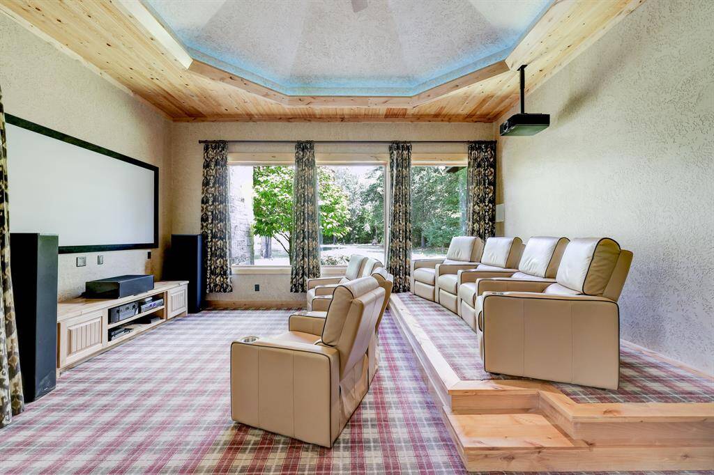 The media room has eight reclining chairs, a projector, and plush printed carpet.