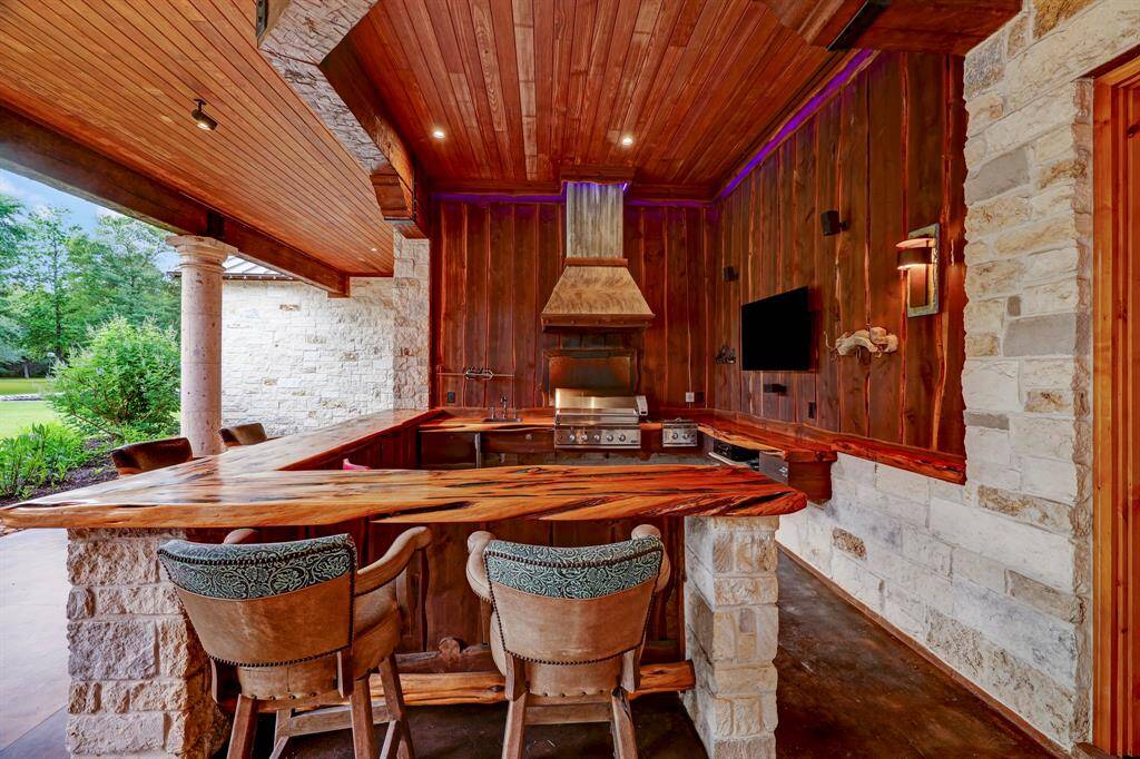 The outdoor kitchen has beautiful cedar countertops with turquoise inlay, sink, and a gas grill.