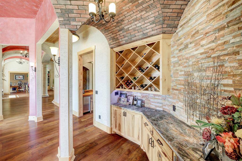 The custom wine bar has a built in wine fridge, brick accents, and a wine storage rack built into the wall.