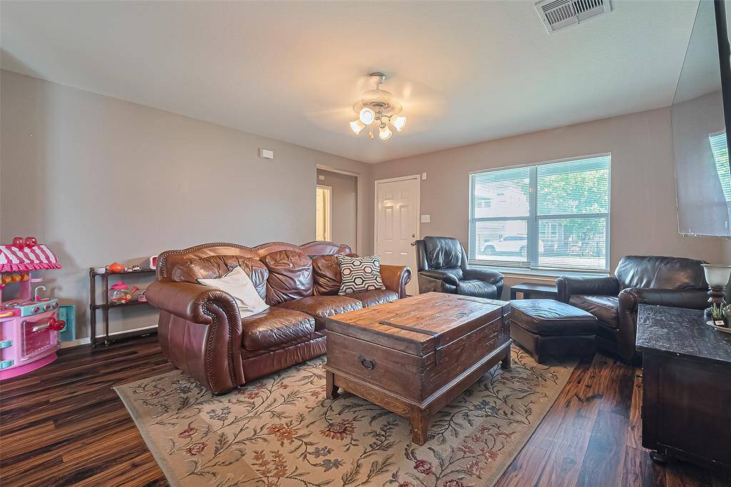 This cozy living room features warm wood-look flooring and a large window allowing natural light.