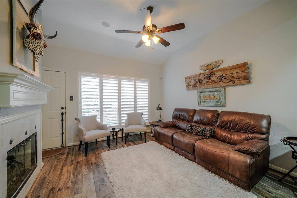 Cozy family room features high ceilings, gaslog fireplace, plantation shutters and a double reclining leather sofa.