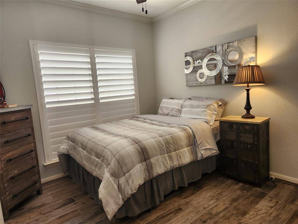 Secondary furnished bedroom features a queen bed, industrial styled furniture and lighting, a large closet and wood look plank tile floors.