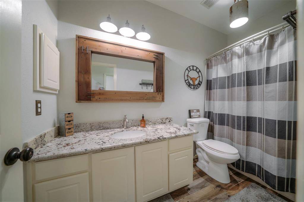 Spacious secondary bathroom, across the hall from the secondary bedroom, features granite, stylish mirror and industrial lighting and bath fixtures.