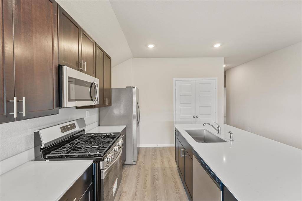Bright and spacious room with light wood flooring, large windows, and a ceiling fan.