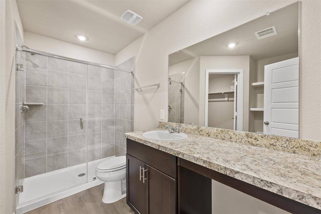 bathroom featuring a spacious walk-in showerjavascript:__doPostBack('m_lbSave','') with glass doors and gray tiling. Adjacent is a walk-in closet