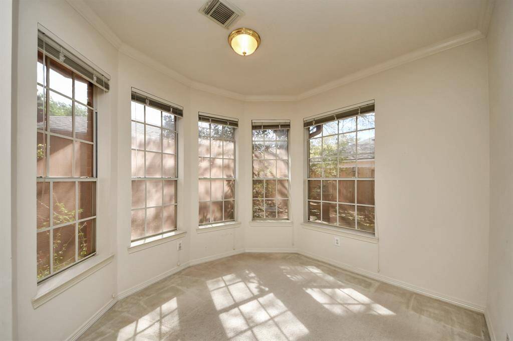 Bright sitting area with large windows and neutral walls, offering plenty of natural light into primary bedroom.