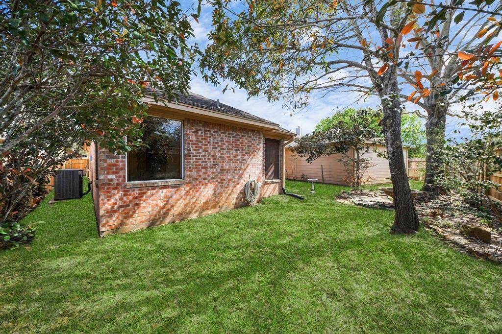 Charming backyard with a well-maintained lawn, mature trees, and a brick exterior. Perfect for outdoor relaxation and enjoying nature.