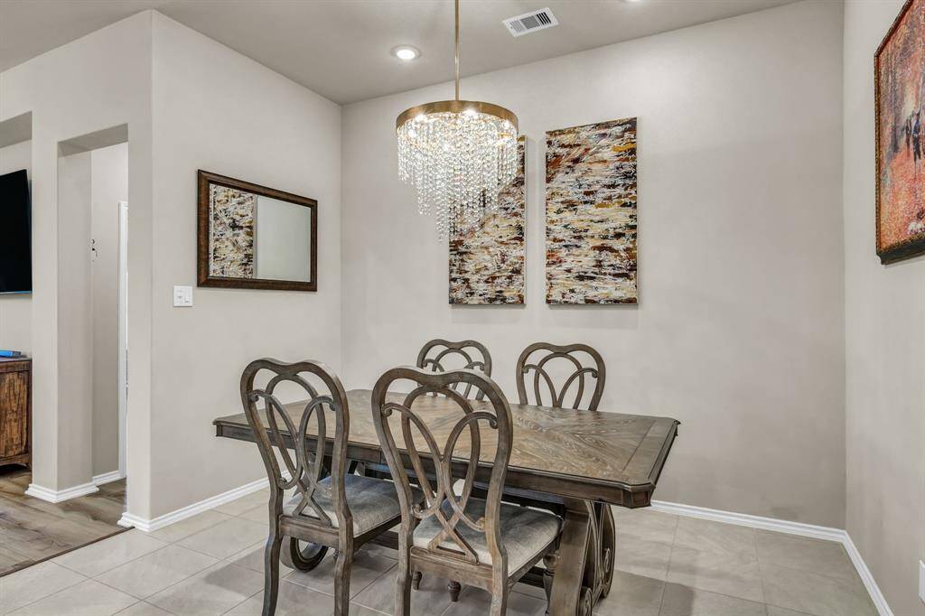 Formal dining area with tile flooring and elegant chandelier.