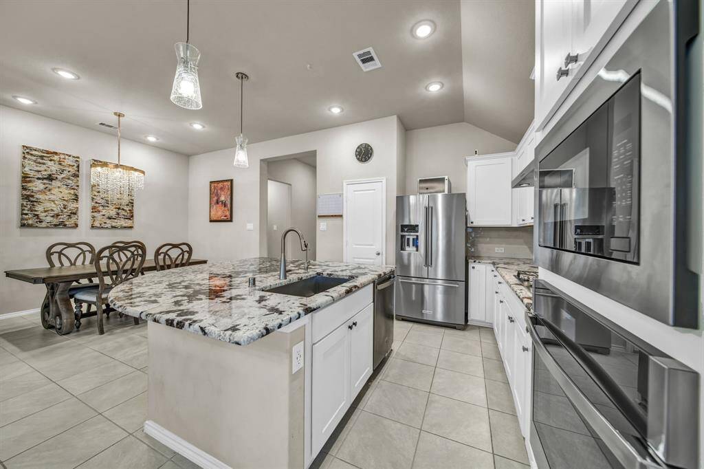Kitchen and dining view with stainless steel appliances and pendant lighting.