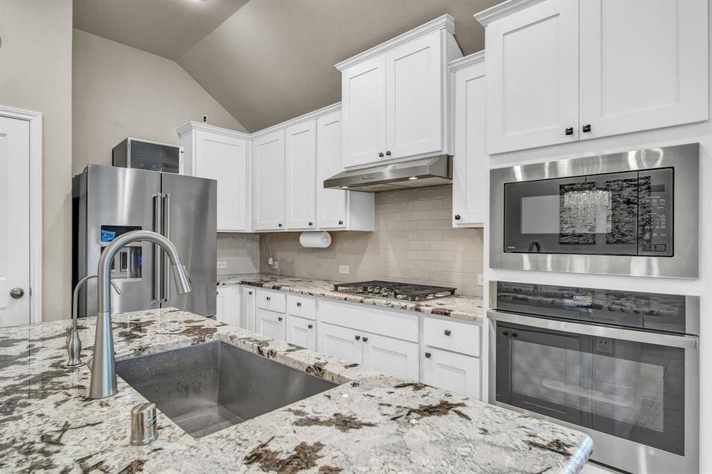 Close-up of kitchen featuring gas cooktop, built-in microwave, and granite.