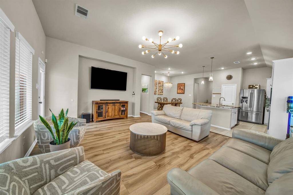 Living room with TV wall, dining area, and kitchen in the background.