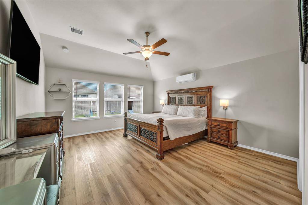 Spacious primary bedroom with wood flooring and natural light.