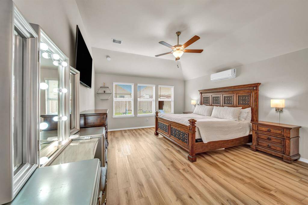 Primary bedroom with vanity area and large windows.