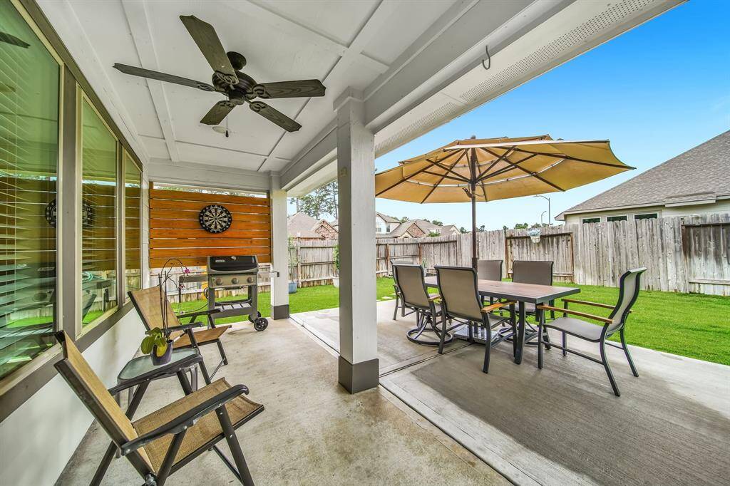 Covered patio with ceiling fan, grill area, and dining setup.