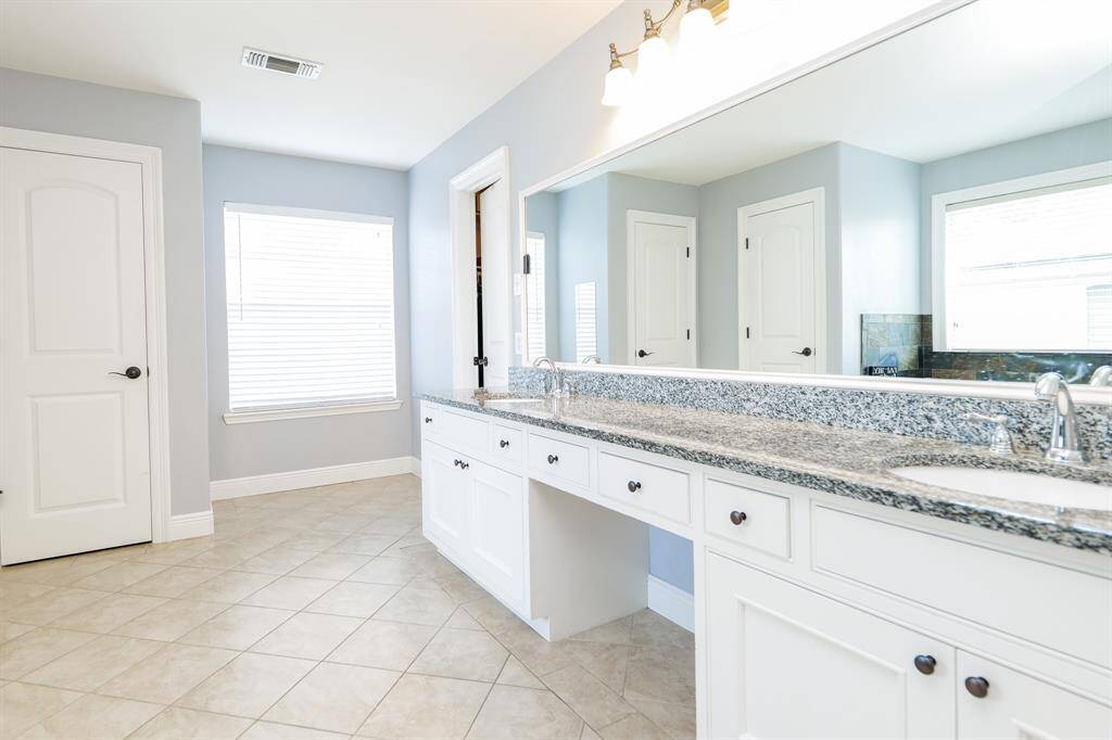 The large master bathroom features double sinks, a spacious separate shower, and a luxurious soaking tub, providing both comfort and functionality.