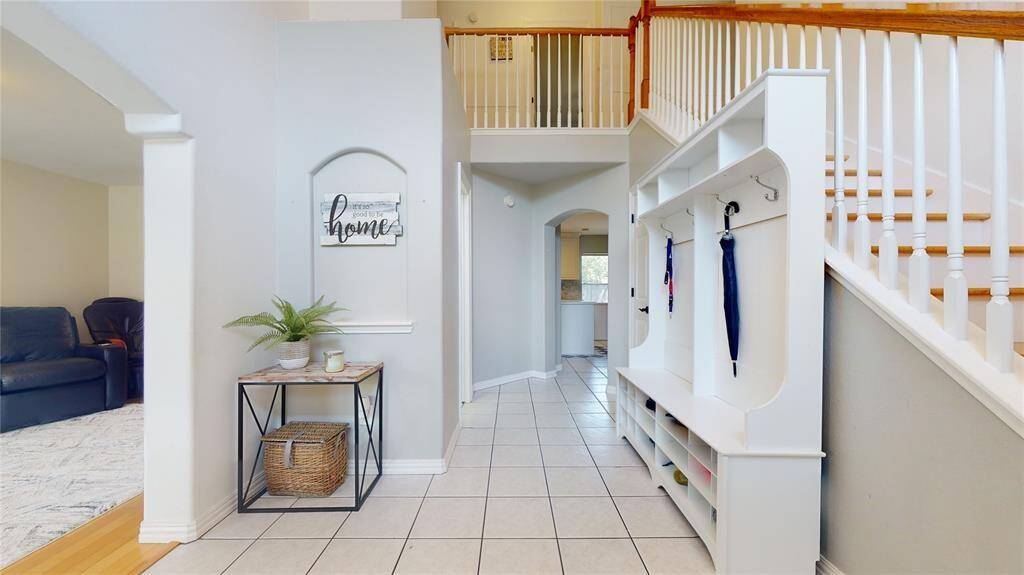 The entrance to the home features a grand two-story foyer with an elegant arched window and abundant natural light.