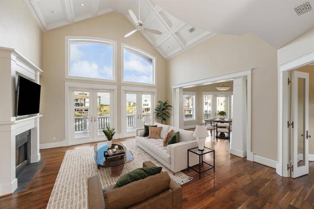 Sunlight pours in through expansive windows and grand doors, framing stunning waterfront views that complete the space with a sense of elegance and tranquility