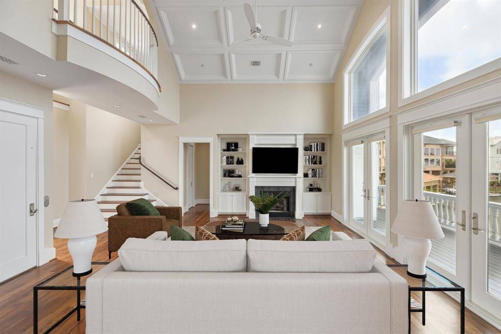 From the dining area, you’re treated to a sweeping view across the living room, where soaring ceilings, elegant finishes, and expansive windows frame the space with natural light and scenic views. The open layout creates a seamless flow, perfect for entertaining
