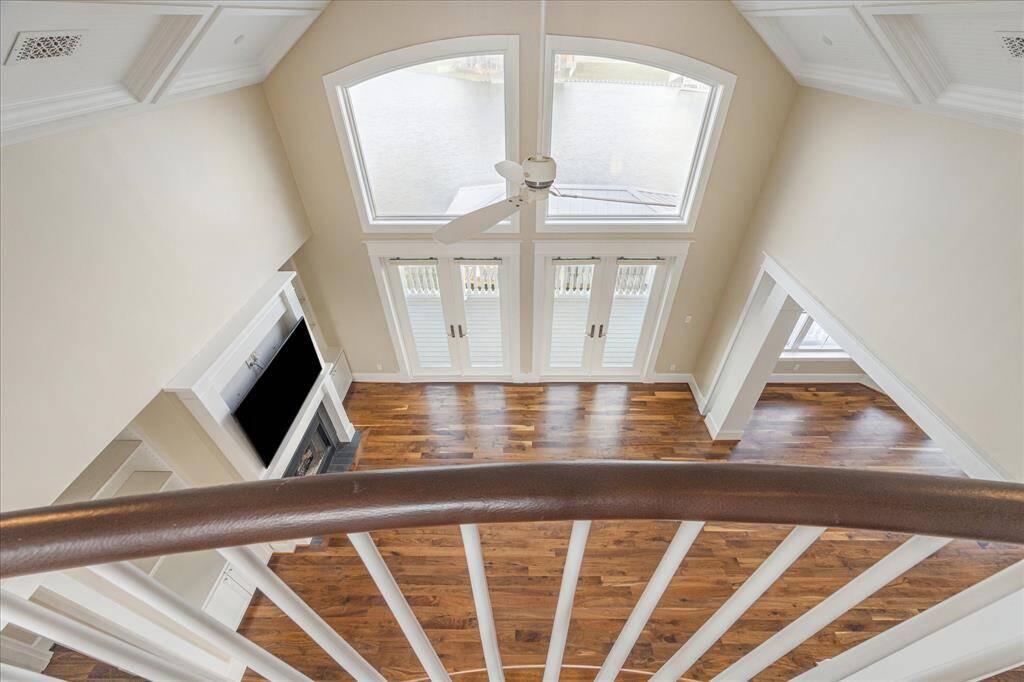 The second-level open balcony overlooks the living area, offering expansive views through a wall of windows that fill the space with natural light