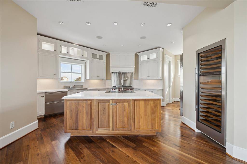 The kitchen showcases a hand-crafted American walnut island paired with custom lacquered cabinetry, all designed with meticulous attention to detail. Features include under-cabinet power outlets, soft-close drawer glides, and distinctive nautical-inspired hardware that adds a touch of coastal charm