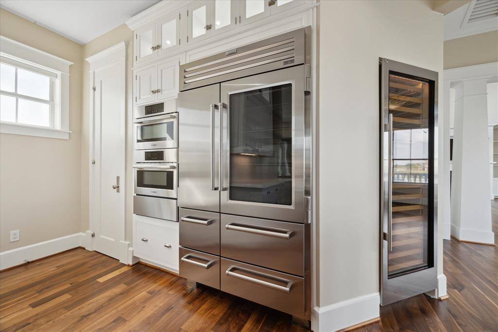 While luxury appliances from SubZero and Wolf—including a glass-front refrigerator with drawer storage—elevate both form and function. Additional highlights include a built-in Miele dishwasher, Bosch double toaster oven with microwave and warming drawers and illuminated upper cabinets, perfect for showcasing your finest pieces