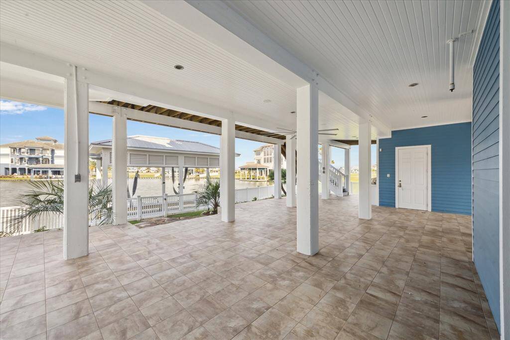 The expansive dockside, water-level entertainment area features a private shower room, beadboard ceilings, ground-floor elevator access to all levels of the home, and durable weatherproof lighting—designed for both comfort and convenience by the water