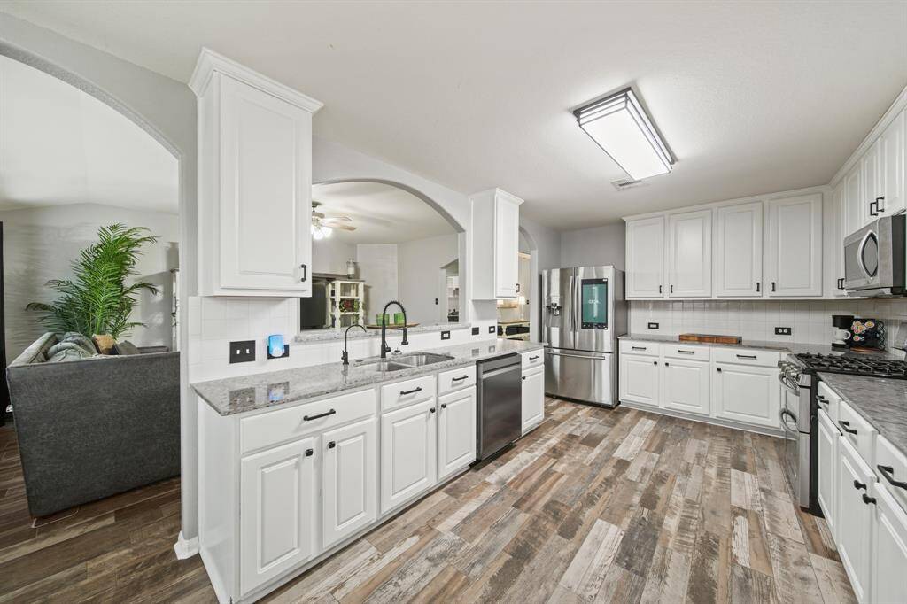 Thoughtfully planned, the kitchen with ceiling mounted lighting and hardwood tile flooring includes 42" painted cabinets capped with crown moulding and accompanied by granite counters with tiled back splashes.