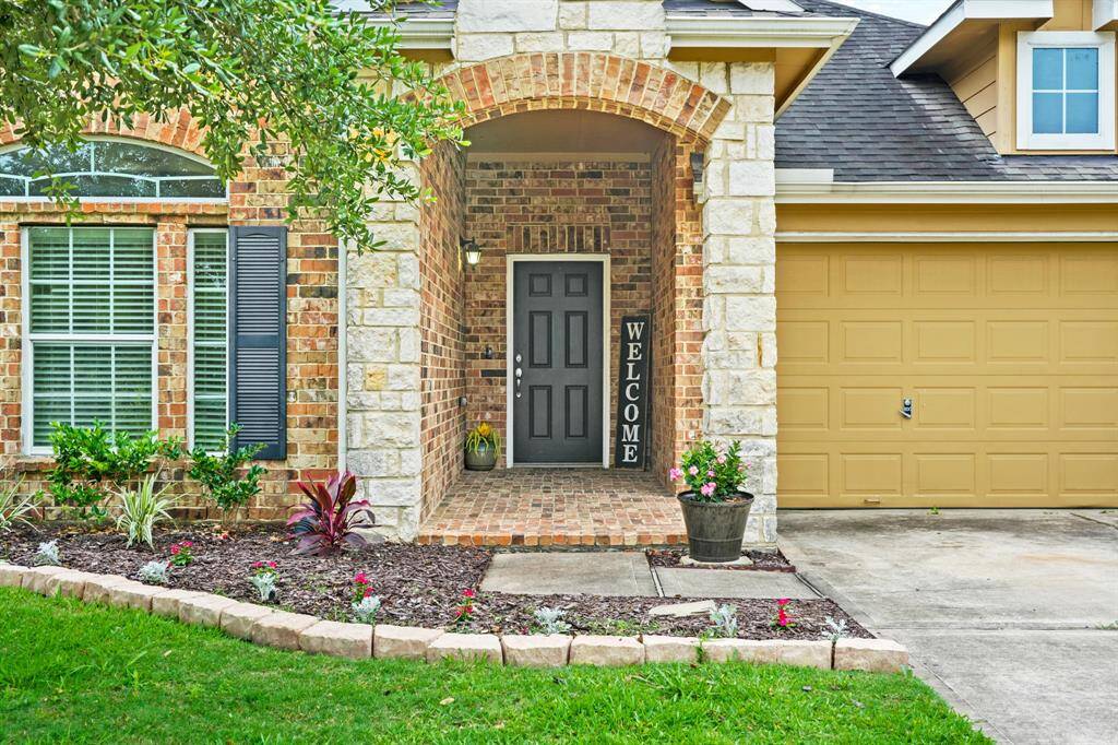 The charming arched & covered front porch surrounded by stone accents includes a brick flooring. A paved walkway leads to the double-wide driveway with access to the home's two car attached garage. The stones outlining the front & backyard flower beds were installed in 2024-2025.