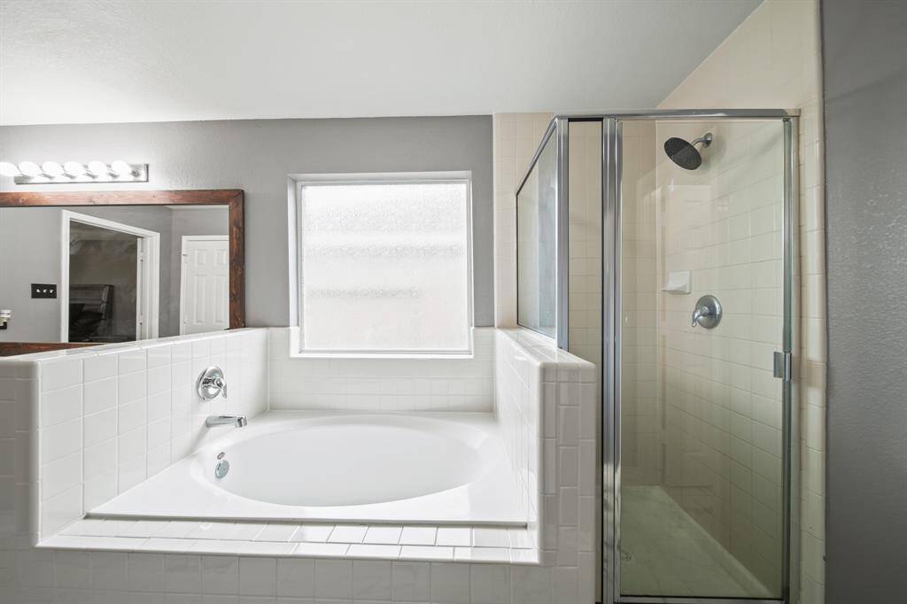 Relax and unwind in the tile surrounded soaking tub with privacy glass window above and nearby floor-to-ceiling tiled & glass enclosed shower.
