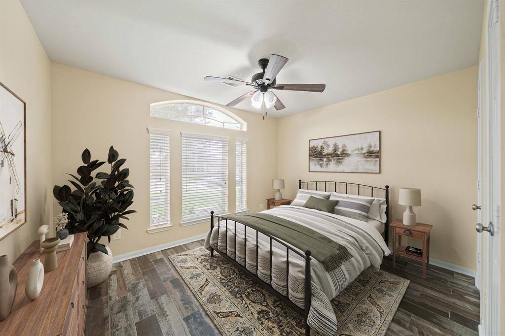 Located on the front of the home with windows & blinds overlooking the front yard, the secondary bedroom features a ceiling fan with lighting & hardwood tile floors.