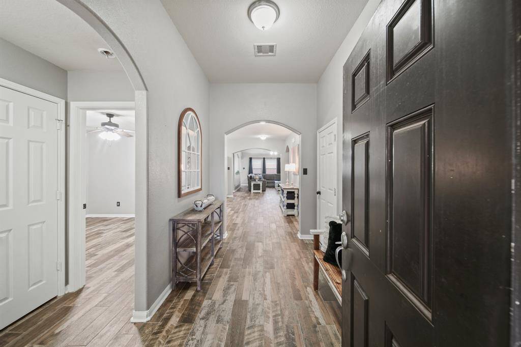 The foyer of the home includes ceiling mounted lighting, space for accent furniture and an arched opening leading to the living spaces of the home. Updated ceiling fans, interior door hardware, baseboards, quarter round moulding & hardwood tile flooring is included throughout the home.