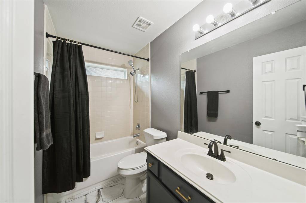 Conveniently located between the second & third bedrooms is the home's second full bath with painted cabinets supporting a solid surface counter top with integrated sink & back splash, wall mounted mirror with lighting, a ceramic tile surrounded combination tub/shower with window above & tile flooring.